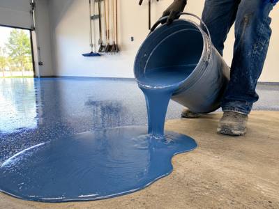 Blue base coat being spread across a freshly ground slab