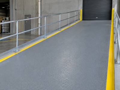 Coated loading ramp with a yellow edge line and a handrail