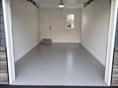 Light grey flake floor in a single garage with the door open