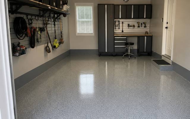 Grey flake garage floor coating in a single bay with wall storage and a workbench